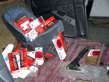 Тайник у підлозі автомобіля „Рено” та частина вилучених цигарок.