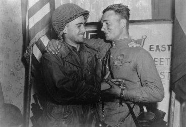 Счастливые лейтенант У. Робертсон и лейтенант А. С. Сильвашко на фоне надписи «Восток встречается с Западом»