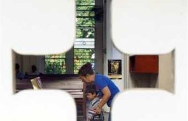 Мать учит ребенка молиться в католическом храме в Куала-Лумпуре