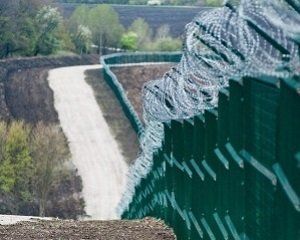 На фотографиях виден длинный забор с колючей проволокой